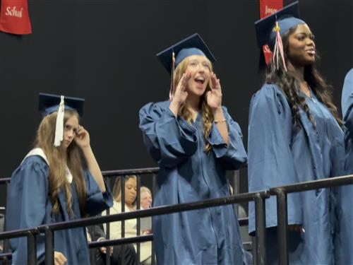 student waving at family from stage to getting her diploma